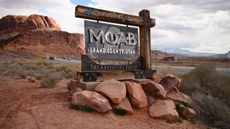 Welcome-to-Moab-Utah-sign-on-a-cloudy-day-with-vehicles-driving-on-Highway-191,-static