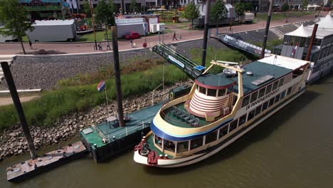 Aerial-view-of-tourist-floating-pancake-restaurant-all-you-can-eat-Pannenkoekenschip-at-anchor-on-the-shore-of-historic-Hanseatic-city-of-Nijmegen-in-waiting-for-passengers-in-river-Maas