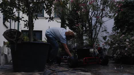 Cinematic-shot-of-mechanic-washing-go-kart-in-his-backyard