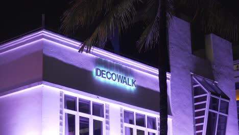 Art-deco-district-at-night-with-neon-lights-sign-of-Deco-Walk-Hotel-Voodoo-lounge-restaurant-bar-in-South-Beach,-Florida-Ocean-Drive-with-people-dining