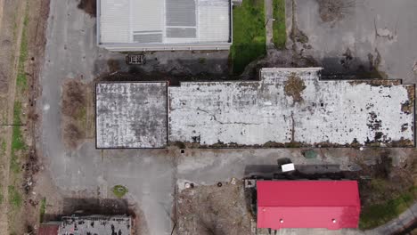 Top-Down-Drone-Footage-Moving-Left-over-a-Large-Abandoned-Brick-Building-with-a-Decaying-Roof