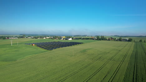 Aerial:-Solar-Panel-Units-and-Wind-Turbine-on-green-grass-field-with-blue-sky