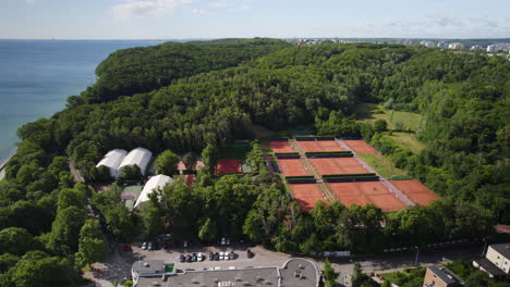 Tennisplätze-Des-Arka-Tennisclubs,-Umgeben-Von-Grünem-Wald-Am-Küstenboulevard-In-Gdynia-–-Umlaufende-Luftaufnahme