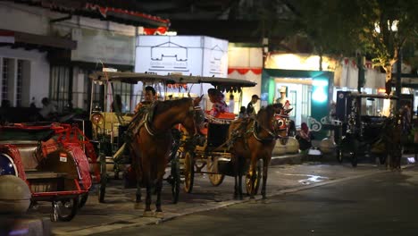 Yogyakarta,-Indonesien,-18.-August-2022:-Eine-Pferdekutsche-Und-Ihr-Fahrer-Warten-In-Der-Nacht-Auf-Der-Malioboro-Straße-Auf-Ihre-Passagiere