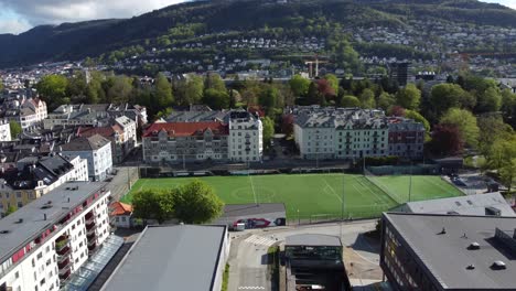 Persons-playing-soccer-on-vibrant-summer-day---playing-field-in-the-middle-of-Bergen-city---Kronstad-Arstad-Bergen-Norway-aerial