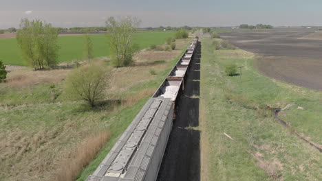 Aerial-drone-shot-day-overhead-of-open-train-cars-moving-on-track-in-by-field