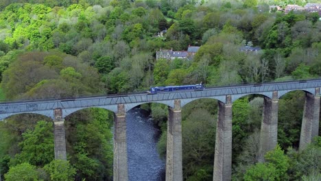 Aerial-view-following-narrow-boat-on-Trevor-basin-Pontcysyllte-aqueduct-crossing-in-Welsh-valley-countryside-slow-zoom-in-shot