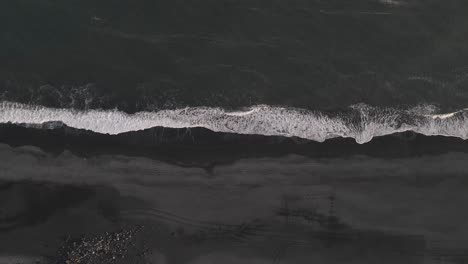 Aerial-vertical-view-of-waves-breaking-on-black-sandy-beach-in-Iceland