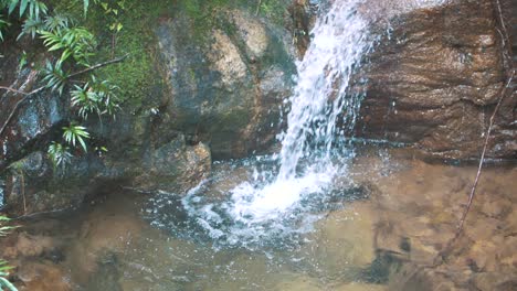 Slow-motion-shot-of-a-small-cascade,-foamy-water-falling,-natural-pools-in-the-forest