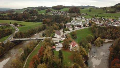 church-in-Lutisburg,-Switzerland,-Aerial-4k-view-of-the-lake-the-hill-and-trees