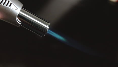 Close-up-Side-View-on-Blow-Torch-Metal-Tip-Being-Used-in-the-Dark,-Blue-Flame-Light