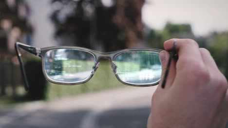 Person-Hält-Augmented-Reality-Smart-Tech-Brille-In-Der-Hand,-Futuristisches-HUD-Zeigt-Codeelemente-In-Der-Linse
