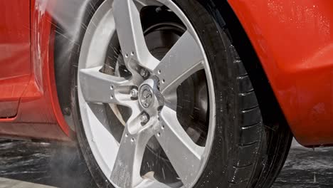 Pressure-washing-alloy-rims-of-red-Mazda-car-in-close-up