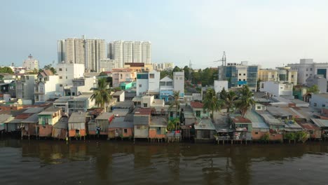 Classic-drone-shot-with-contrast-of-old-and-new-buildings-along-the-canal-waterfront-in-district-eight-of-Ho-Chi-Minh-City,-Vietnam