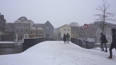 Leiden-town-in-snow,-People-crossing-Rhine-bridge,-Netherlands-winter