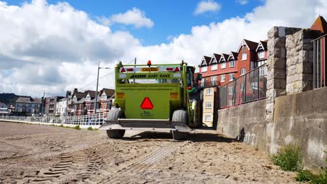 Conwy-council-Surf-Rake-seaside-beach-tidy-machine-pulled-behind-tractor-on-sunny-North-Wales-promenade