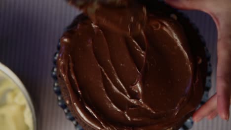 Topping-a-cake-with-thick-chocolate-frosting---top-down-view