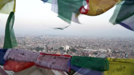 Ondeando-Banderas-Coloridas-Desde-La-Estupa-Swayambhunath-Con-Vistas-Al-Paisaje-Urbano-De-Katmandú,-Nepal
