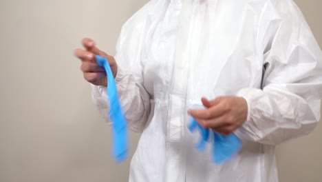 worker-in-ppe-suit-taking-off-latex-gloves