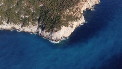 Luftaufnahme:-Hügelwaldinselklippe-Am-Meeresufer-Mit-Blauem-Wasser-Bei-Lefkada,-Griechenland:-Drohne-Fliegt-Von-Oben-Nach-Unten