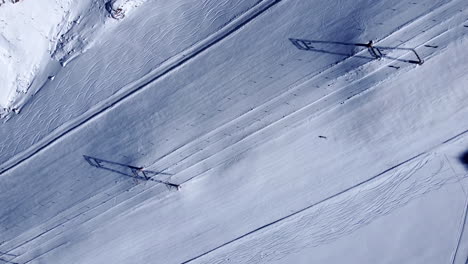 High-aerial-shot-looking-down-on-a-lone-snow-skier-casually-carving-left-and-right-slaloming-down-a-steep-majestic-mountain-slope-at-Val-Senales-Glacier,-a-popular-ski-resort,-Italy,-Europe