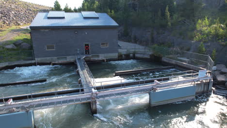 A-beautiful-drone-close-up-of-a-small-hydro-electric-plant-creating-and-generating-electricity-at-a-dam-in-Island-park
