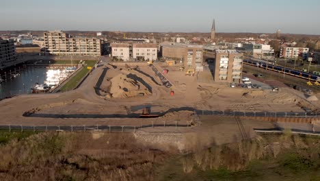 Sideways-aerial-view-showing-a-construction-site-of-the-new-Kade-Zuid-luxury-apartment-building-project-in-Noorderhaven-neighbourhood-in-Hanseatic-city-Zutphen,-The-Netherlands