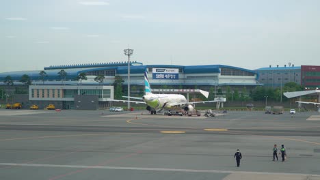 Flughafenpersonal-Zu-Fuß-Mit-Air-Busan-Airbus-Geparkt-Auf-Dem-Vorfeld-Des-Internationalen-Flughafens-Gimhae-In-Busan,-Südkorea