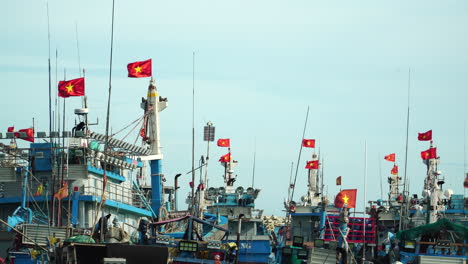 Vietnamese-flags-wave-on-fishing-ships-anchored-in-Vinh-Hy-harbour,-Vietnam