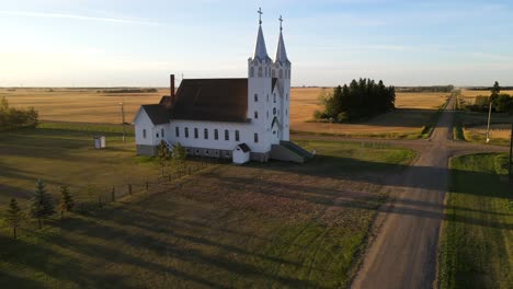 Aerial-shot-of-roman-catholic-church-in-north-American-prairie-during-sunset