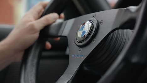 Hände-Auf-Einem-Schwarzen,-Schlichten-Custom-Lenkrad-Mit-BMW-Logo