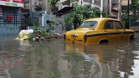 Yellow-taxi-vehicle-stuck-in-flooded-road-in-Kolkata,-India