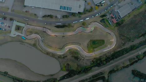 Static-drone-perspective-of-go-karts-driving-around-go-kart-track-during-evening-light