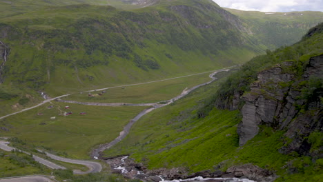 Aerial-shot-flying-through-a-mountain-valley-with-a-river-and-road-in-Norway
