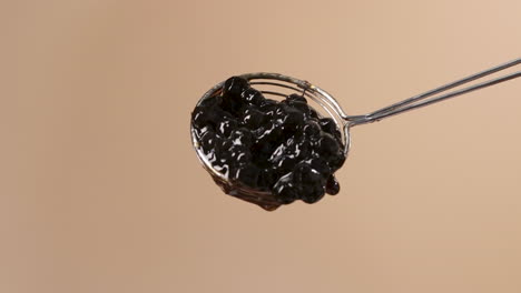 Juicy-Black-Tapioca-Pearls-Slowly-Falling-from-Round-Spider-Strainer