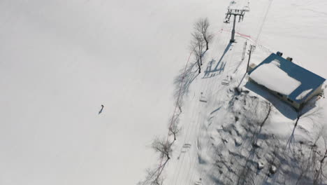 Aerial-View-Of-Tourists-Skiing-On-The-Downward-Slope-Near-The-Ski-Lifts-In-Mountain-Resort-Of-Okuhida-Hirayu,-Gifu,-Japan