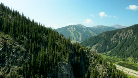 Wir-Fliegen-Direkt-über-Einen-Berggipfel-Und-Kiefern-Und-Zeigen-Das-Skigebiet-Copper-Mountain-In-Colorado