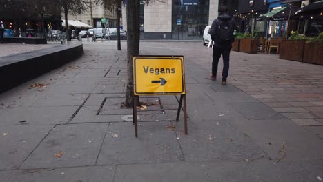 A-man-walks-past-a-yellow-vegan-sign