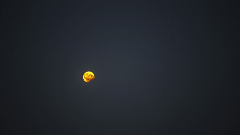 Time-lapse-shot-of-golden-full-moon-rising-up-against-dark-sky-during-night