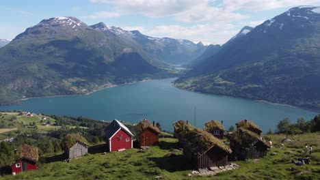 Raksetra-Loen-forward-moving-aerial-over-rural-cottage-rooftops-showing-amazing-view-of-Nordfjord-Olden-and-Loen-in-mountainous-landscape---Norway