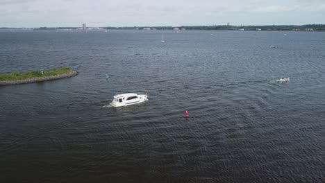 Aerial-view-of-small-yacht-departing-from-the-harbor-and-sailing-onto-the-lake