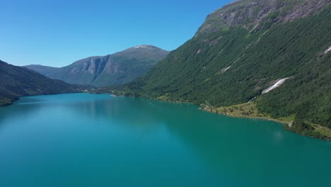 Lake-Oldevatn-Norway---Huge-crispy-clean-glacial-green-freshwater-lake-in-Olden-Norway---Forward-moving-aerial-close-to-hillside