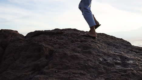 Mujer-Caminando-Sobre-Rocas-Costeras-En-La-Playa---Tiro-De-Seguimiento