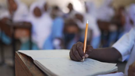 Nahaufnahme-Eines-Afrikanisch-schwarzen-Kindes-Mit-Bleistift,-Das-Hausaufgaben-In-Einer-Islamischen-Schule-In-Afrika-Schreibt,-4K
