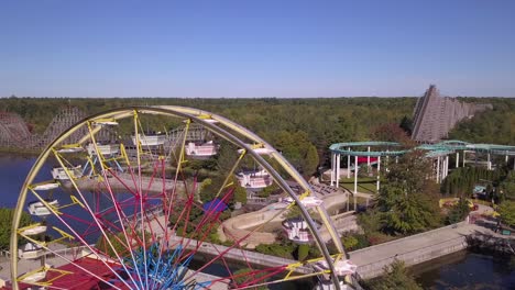 Rising-aerial-of-ferris-wheel,-rollercoasters-and-lake-in-Michigan