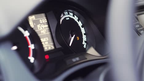 Car-start-and-low-fuel-level-symbol-showing-on-dashboard,-extreme-closeup-side-view