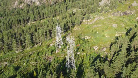 Approaching-massive-high-voltage-power-lines-in-Norwegian-mountain---Distribution-and-export-of-electricity-from-renewable-energy-sources---Aerial-from-far-to-closeup