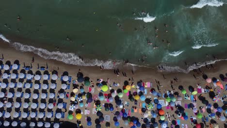 Vogelperspektive-Auf-Menschen-An-Einem-Belebten-Strand-Im-Sommer-Mit-Sonnenschirmen-Und-Dem-Meer