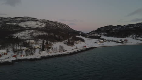 Pueblo-ártico-Nevado-Con-Casas-Frente-Al-Mar-Durante-La-Noche-Polar-En-Noruega