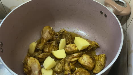 Gewürfelte-Kartoffeln-In-Einen-Brutzelnden-Hähnchen-Curry-Topf-Geben